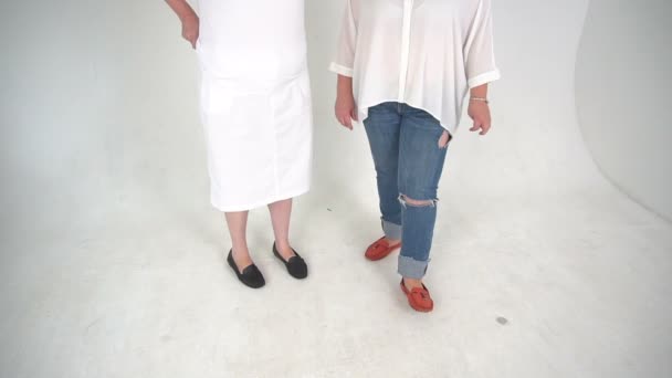 Dos mujeres irreconocibles vestidas con jeans y vestidas en un suelo aislado sobre fondo blanco . — Vídeos de Stock