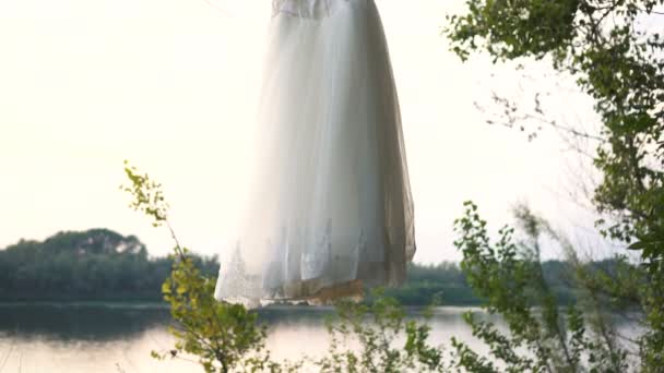 Весільна біла сукня висить на дереві — стокове відео