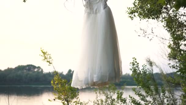 Vestido de novia casual hecho a mano blanco cuelga de la rama del árbol en el jardín — Vídeos de Stock