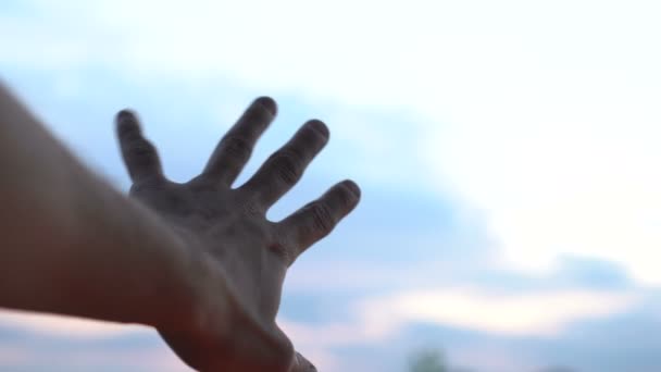 Mão esquerda estendida em direção ao céu azul na tentativa de alcançar as nuvens — Vídeo de Stock