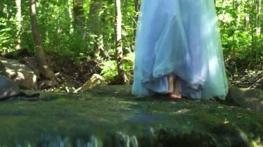 Yürüyen kadın bir elbise ve adımlarla vahşi orman orman üzerinde zemin temiz dağ Nehri üzerinde seyahat.