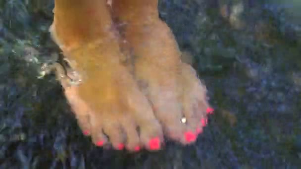 Girl with pink pedicure standing over river with her feet in the water — Stock Video