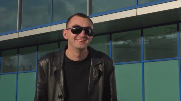 Mladý muž v kožené bundě a sluneční brýle překvapil venkovní — Stock video