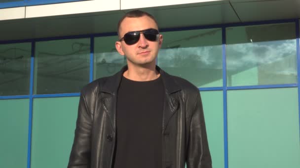 Young man in leather jacket and sunglasses standing outdoor — Stock Video