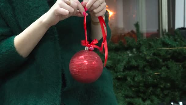 Женская рука с красной новогодней игрушкой и маникюром. Рождественские приготовления — стоковое видео
