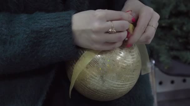 Mulher em verde camisola de lã quente segurando brinquedo bolas decorativas douradas nas mãos — Vídeo de Stock