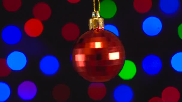 Christmas red mirror ball toy is spinning close-up. Decor with new year tree lights twinkling. — Stock Video