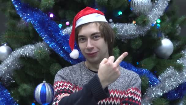 Schöner junger Mann trägt Weihnachtsmütze und zeigt Mittelfinger gestikulierenden Fick. — Stockvideo