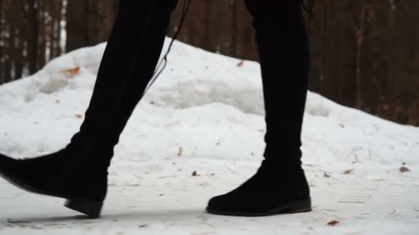 Nahaufnahme von Frauenfüßen in Stiefeln, die durch die Schneewüste laufen. — Stockvideo