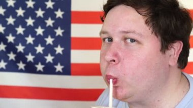 Amerikan Bayrağı önünde samandan kokteyl içen bir adamın yakın çekim