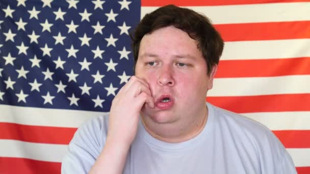 Young man thinking about something on the background of an USA flag — 비디오