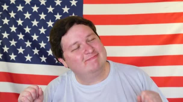 Junger Mann amüsiert sich und tanzt auf dem Hintergrund einer US-Flagge — Stockvideo