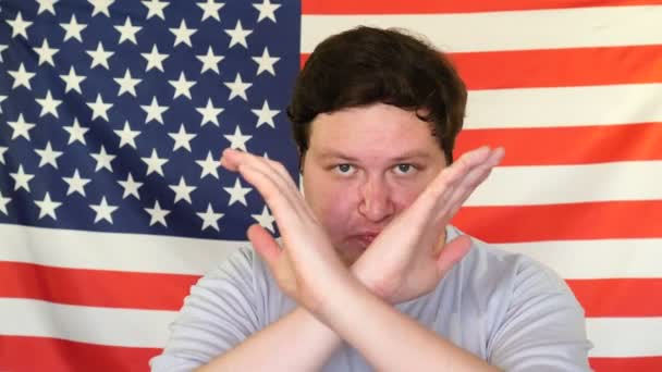 Человек со скрещенными руками показывает стоп-жест на фоне флага США — стоковое видео