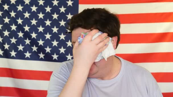 Fet man, torka svetten med en näsduk på bakgrunden av en USA flagga — Stockvideo