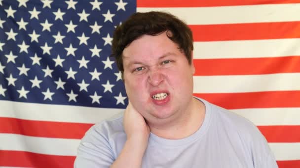 Portré fiatal férfi nyaki fájdalom a háttérben egy amerikai zászló — Stock videók