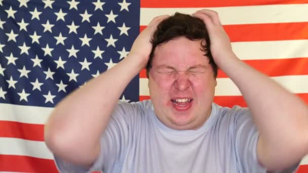 Πορτραίτο του νεαρού ανήσυχος χοντρός άνθρωπος με στρες στο φόντο της σημαίας των ΗΠΑ — Αρχείο Βίντεο