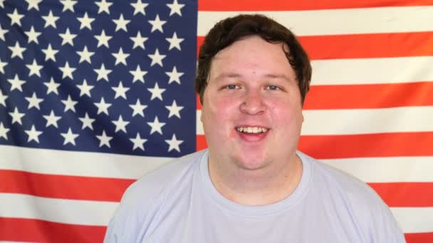 Young fat man winking on the background of an USA flag — 비디오