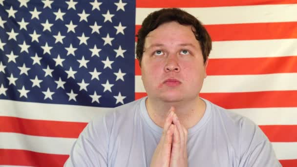 Young fat man praying on the background of an USA flag — 비디오