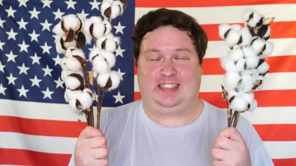 Porträtt av Happy man Holding Cotton Branch på bakgrunden av en USA flagga — Stockvideo