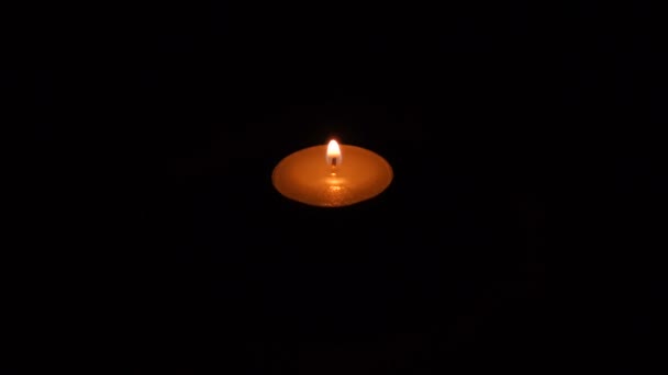 Eine helle Kerze brennt hell vor schwarzem Hintergrund — Stockvideo