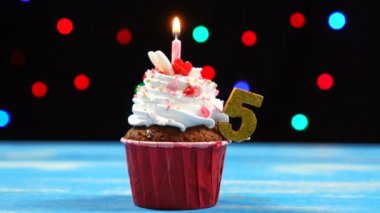 Yanan mum ve çok renkli bulanık ışıklar arka plan üzerinde numara 5 ile Lezzetli doğum günü cupcake