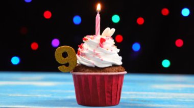 Yanan mum ve çok renkli bulanık ışıklar arka plan üzerinde numara 9 ile Lezzetli doğum günü cupcake