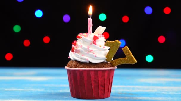 Výborný narozeninový dort s hořící svíčkou a číslo 17 na pozadí barevných rozmazaných světel — Stock video