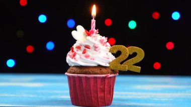 Yanan mum ve çok renkli bulanık ışıklar arka plan üzerinde sayısı 22 ile Lezzetli doğum günü cupcake