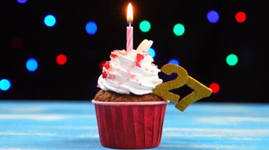 Yanan mum ve çok renkli bulanık ışıklar arka plan üzerinde sayısı 27 ile Lezzetli doğum günü cupcake