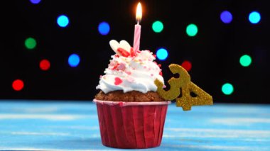 Yanan mum ve çok renkli bulanık ışıklar arka plan üzerinde sayısı 34 ile Lezzetli doğum günü cupcake