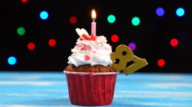 Yanan mum ve çok renkli bulanık ışıklar arka plan üzerinde sayı 81 ile Lezzetli doğum günü cupcake