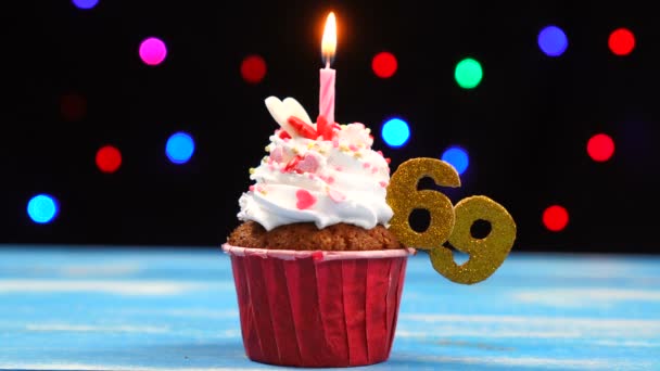 Délicieux cupcake d'anniversaire avec bougie allumée et numéro 69 sur fond de lumières floues multicolores — Video