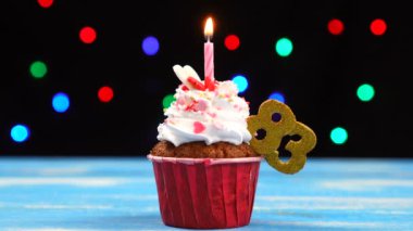 Yanan mum ve çok renkli bulanık ışıklar arka plan üzerinde sayı 83 ile Lezzetli doğum günü cupcake