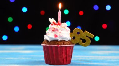 Yanan mum ve çok renkli bulanık ışıklar arka plan üzerinde sayı 85 ile Lezzetli doğum günü cupcake