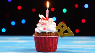 Çok renkli bulanık ışıklar arka planda yanan mum ve sayı 87 ile Lezzetli doğum günü cupcake