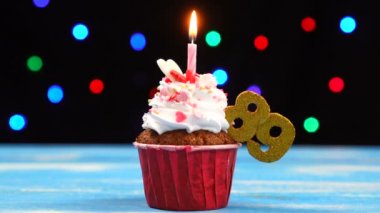 Yanan mum ve çok renkli bulanık ışıklar arka plan üzerinde sayı 89 ile Lezzetli doğum günü cupcake