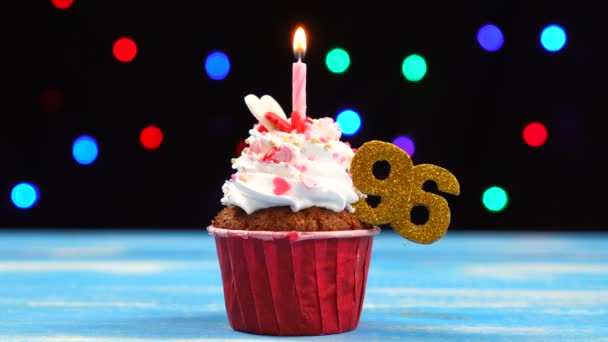 Delicioso cupcake de cumpleaños con vela encendida y número 96 sobre fondo de luces borrosas multicolores — Vídeos de Stock