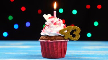 Yanan mum ve çok renkli bulanık ışıklar arka plan üzerinde sayı 43 ile Lezzetli doğum günü cupcake