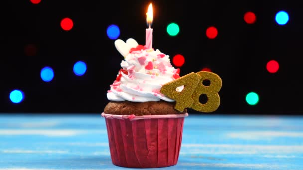 Delicioso cupcake de cumpleaños con vela encendida y número 48 sobre fondo de luces borrosas multicolores — Vídeos de Stock