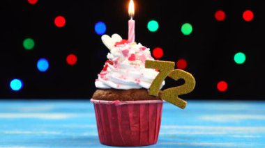 Yanan mum ve çok renkli bulanık ışıklar arka plan üzerinde numara 72 ile Lezzetli doğum günü cupcake