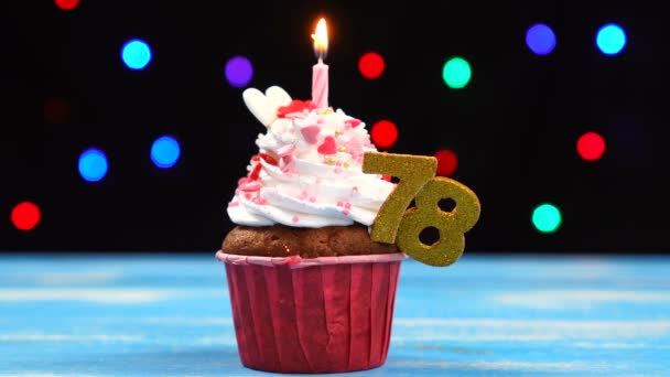 Delicioso cupcake de aniversário com vela ardente e número 78 em luzes borradas multicoloridas fundo — Vídeo de Stock