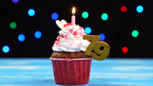 Heerlijke Verjaardag Cupcake met brandende kaars en nummer 79 op veelkleurige wazig lichten achtergrond — Stockvideo