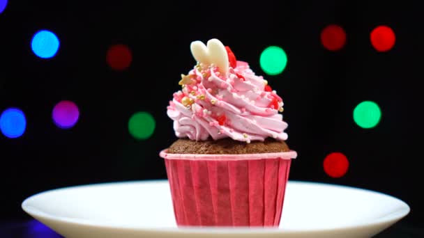 Delicioso cupcake rematado con remolino de glaseado de fresa dulce gira en el plato — Vídeo de stock