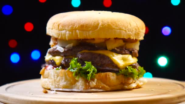 Hamburguesa apetecible carne girando sobre coloridas luces borrosas fondo — Vídeos de Stock