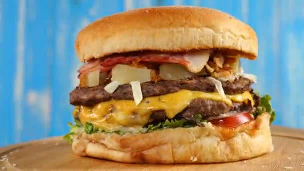 Hamburger appétissant frais tournant sur fond bleu . — Video