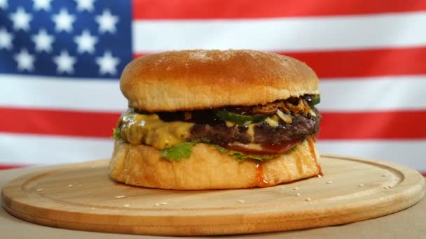 Fresh juicy hamburger rotating on US flag background. — Stock Video