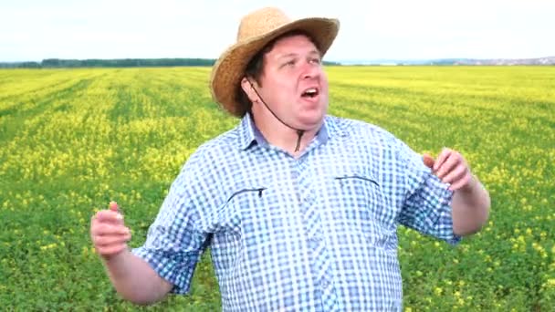 驚いた農家は、手を上げて晴れた日に野原で大きく開いた口で、とてもショックを受け、非常に幸せです — ストック動画