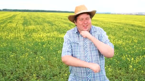 Счастливый толстый мужчина фермер весело танцует среди маленьких зеленых ростков на поле в солнечный день . — стоковое видео