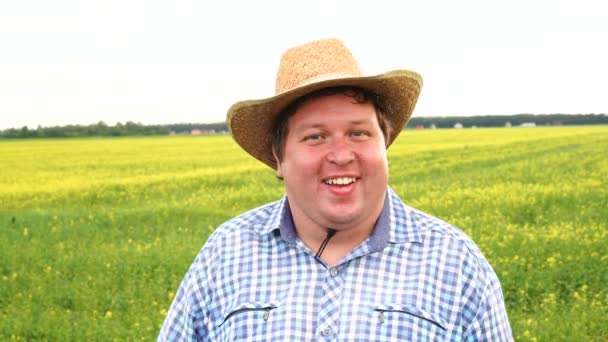 Happy farmer standing in field winking and smiling, wear cowboy hat on a sunny day — Stock Video