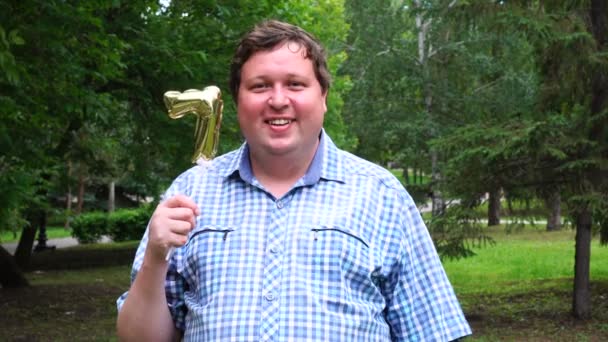 Big man innehar Golden Balloon göra 7 nummer utomhus. 7-års jubileum fest — Stockvideo